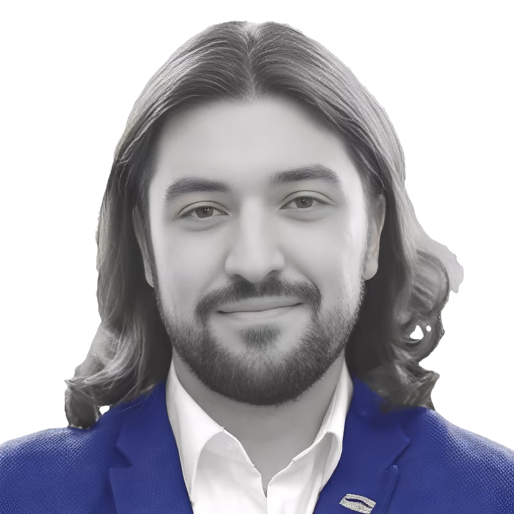 A head-and-shoulders portrait of David Osipov, a man with long dark hair and a beard, smiling warmly. He is wearing a white collared shirt and a vibrant blue blazer with a pin on the lapel. The image is styled in black and white with the blazer as the only element in color.