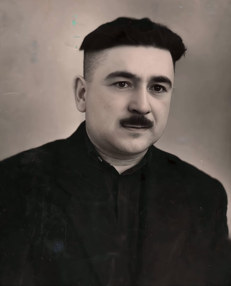 A sepia-toned, historical studio portrait of Georgiy Pavlovich Osipov. He is a young man with fair skin, dark, deep-set eyes, and a prominent dark mustache, looking directly at the camera with a calm expression. His thick, dark hair is styled in an undercut, short on the sides and longer on top. He is wearing a dark, high-collared shirt under a dark jacket. The photograph shows signs of age, including some scratches and fading, set against a plain, light-colored background.